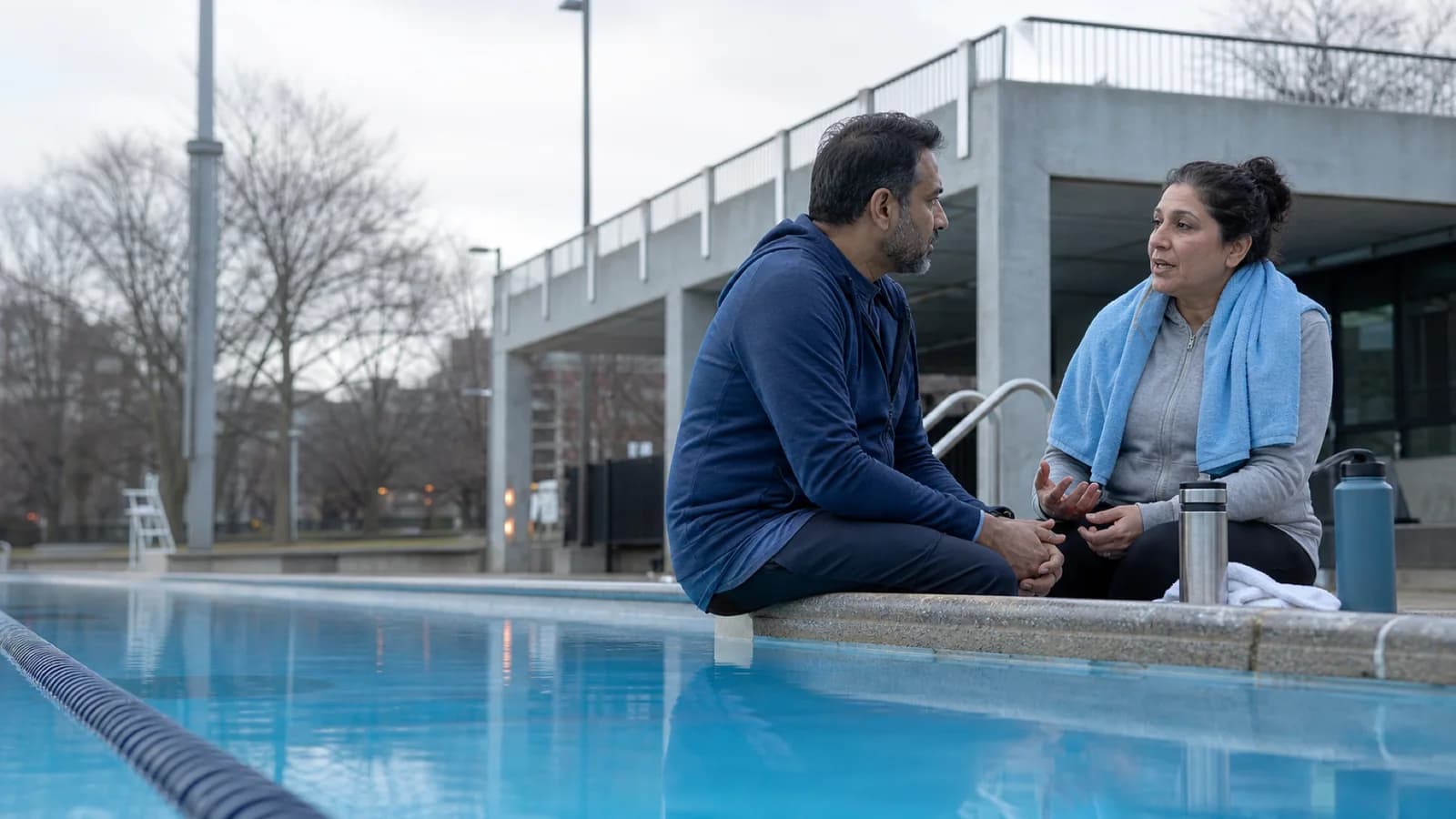 A middle-aged brother and sister talk calmly after a swim at a Toronto public pool.